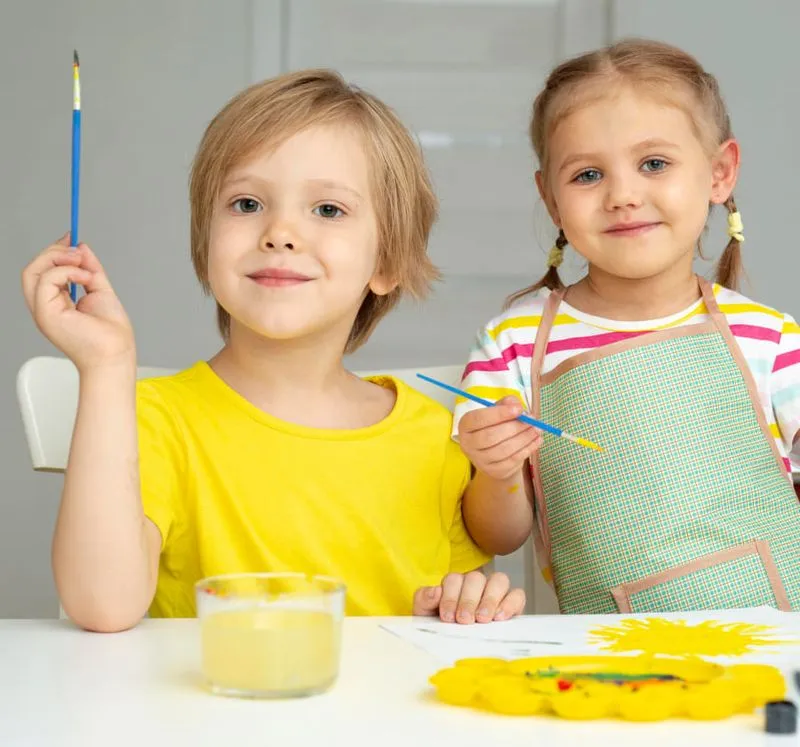 Two children painting together in a bright, safe environment